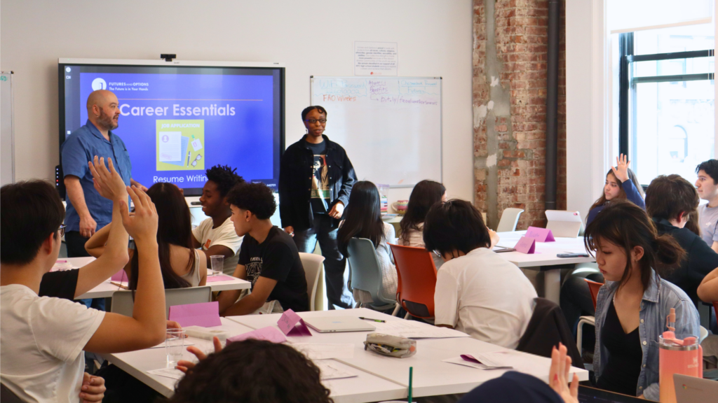 Students raise hands in Career Essentials resume writing workshop.